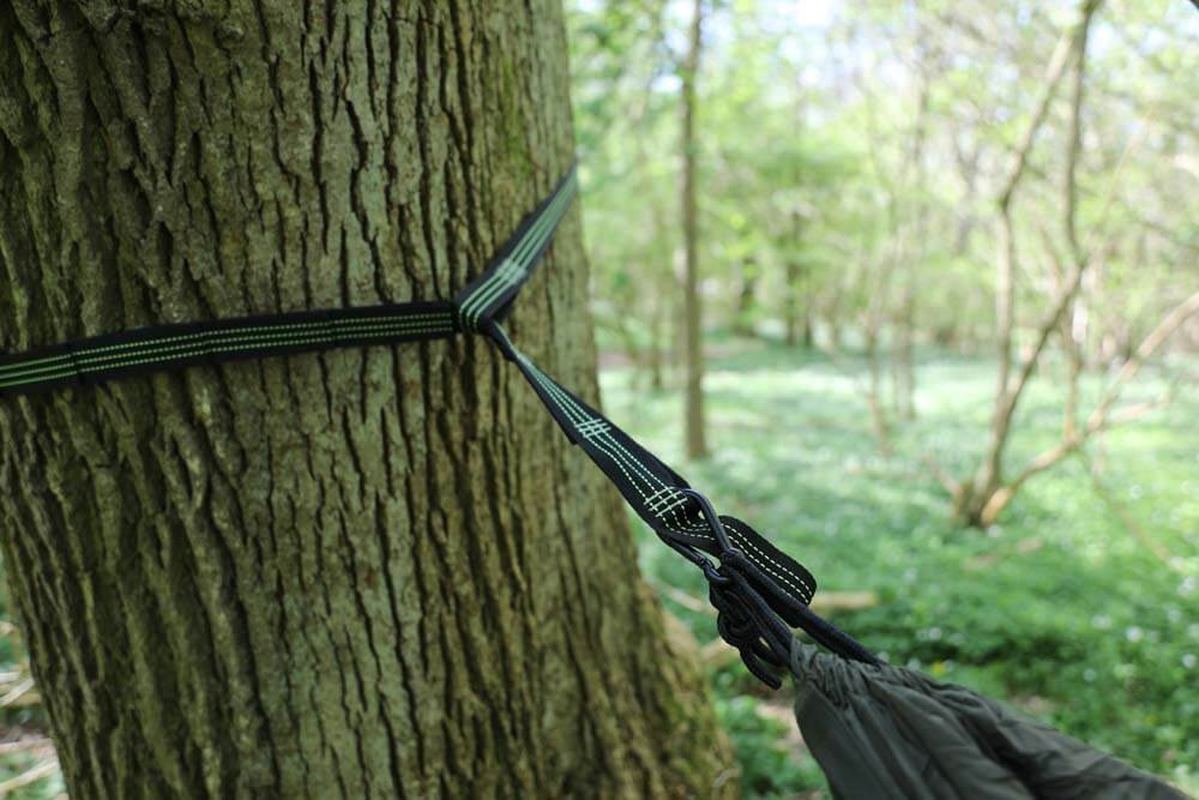 Svart treesaver rem vänd runt trädstam med knut för hängmatta, bred design som skyddar barken vid utomhusbruk