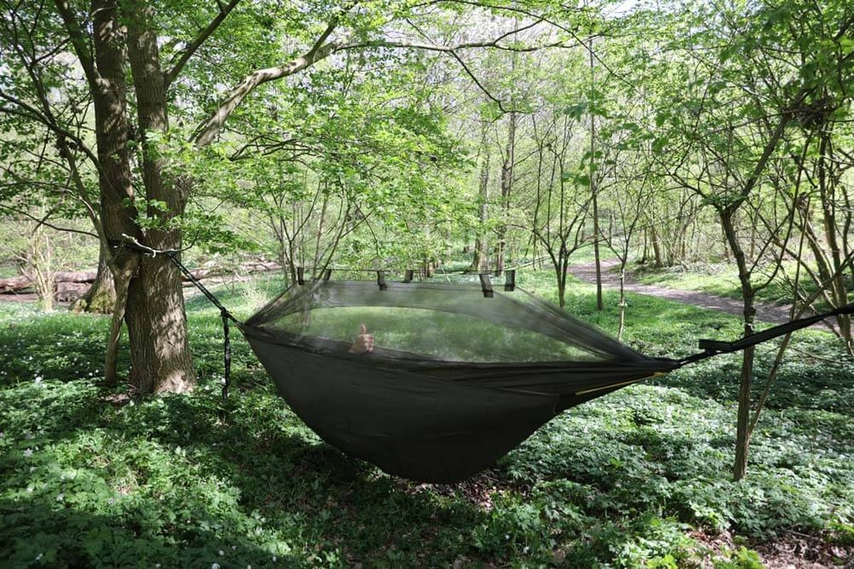 Mörkgrön hängmatta med nät i skog