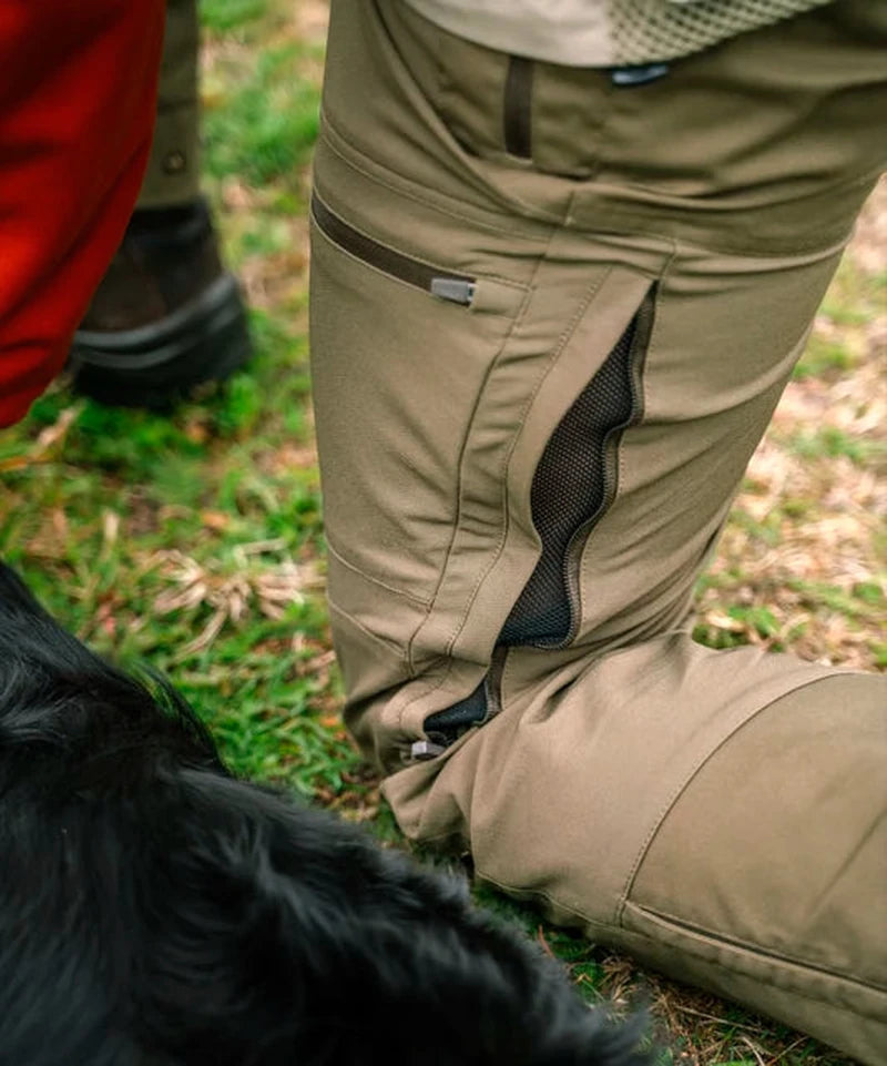 Närm vy av olivgröna hybridbyxors stretchpaneler med mesh och dragkedjeficka