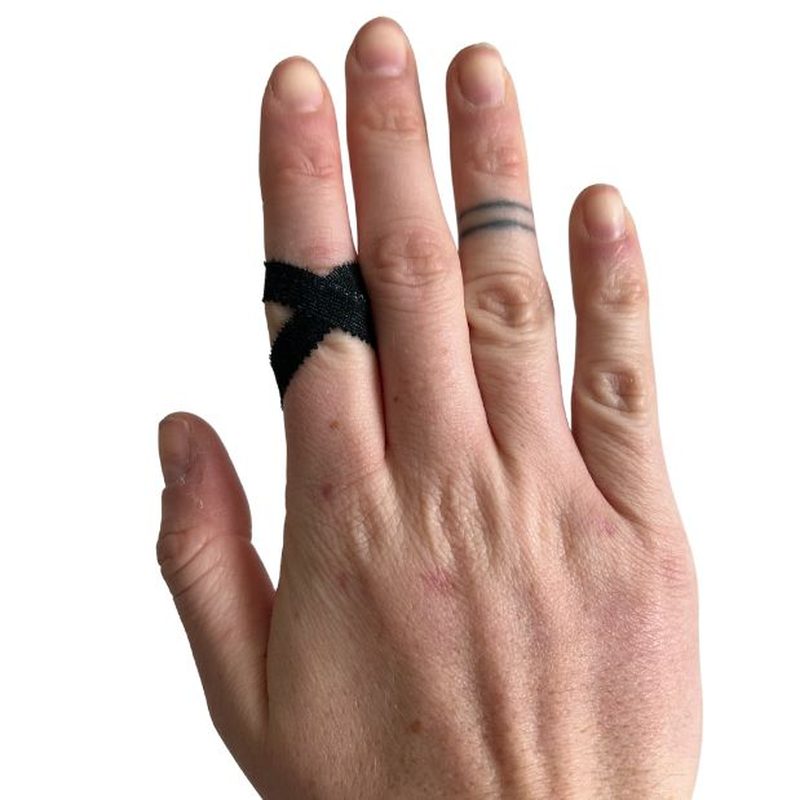 Svart finger-tejp applicerad i X-format för klätterstöd