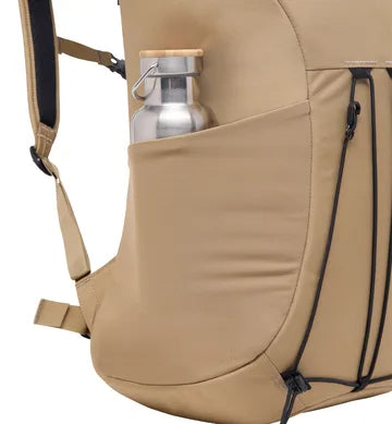 Närbild beige ryggsäck med silverfärgad vattenflaska i sidoficka och elastisk snörning
