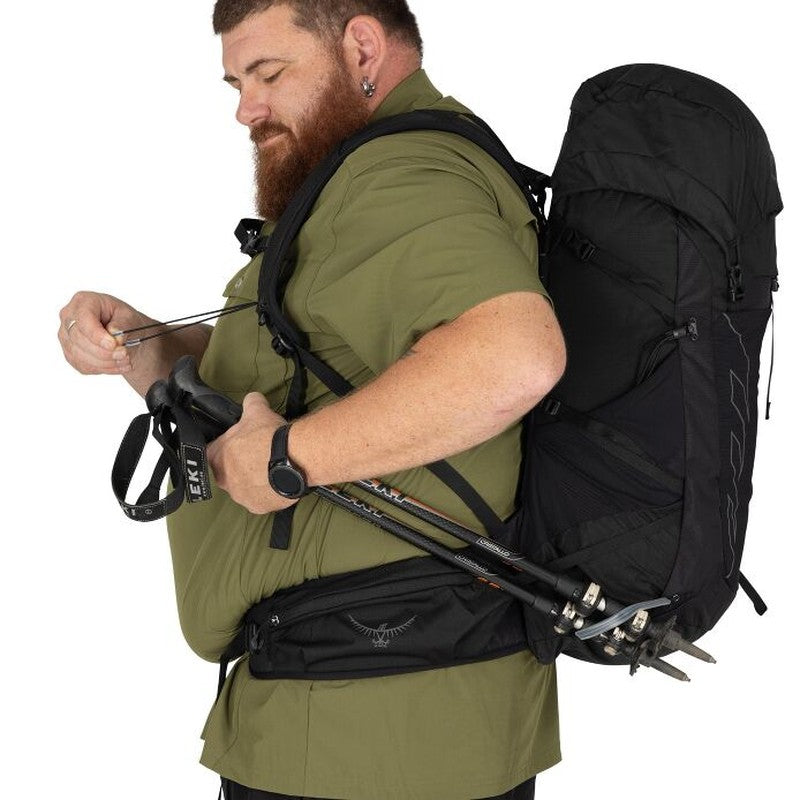 Man bär vandringsstavar på svart Osprey Talon 33