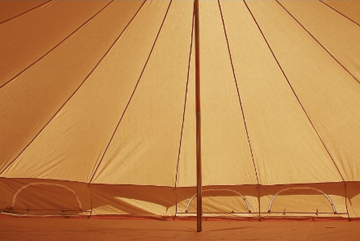 Interiör av beige campingtält med trästativ och fönsteröppningar