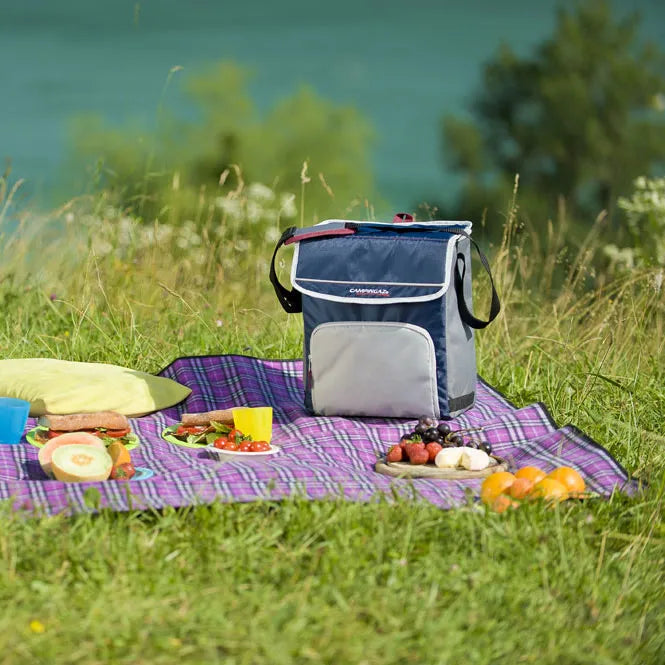 Marinblå Fold N´ Cool kylväska vid picknick med frukt och smörgåsar