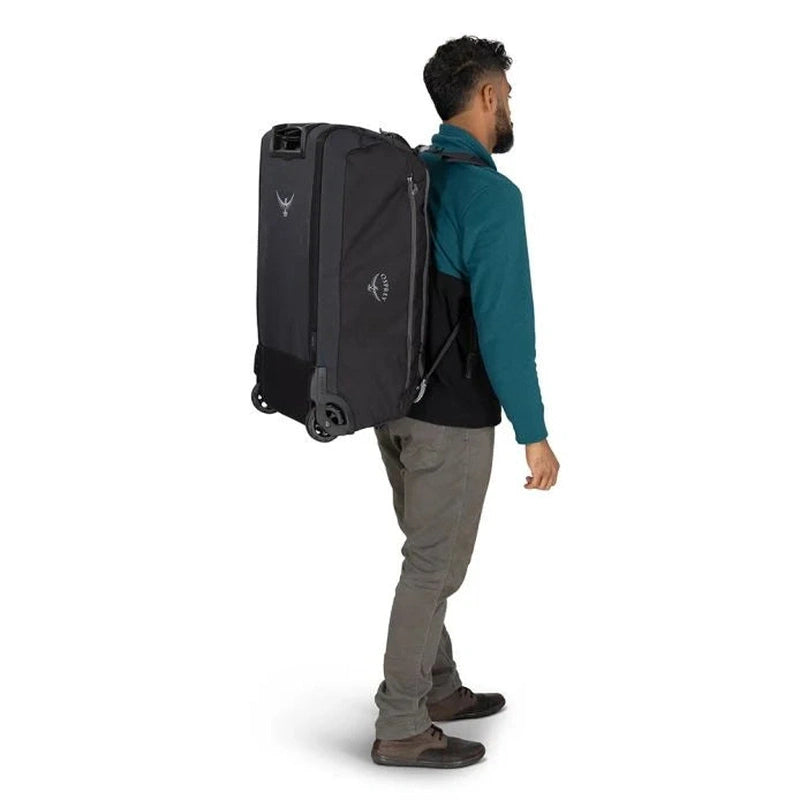 Man bär Osprey Daylite Wheeled Duffelbag 85 svart som ryggsäck