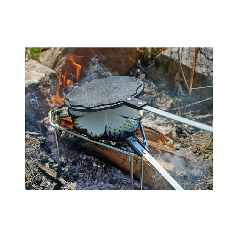Gjutjärnsvåffeljärn med hjärtformade våfflor över öppen eld
