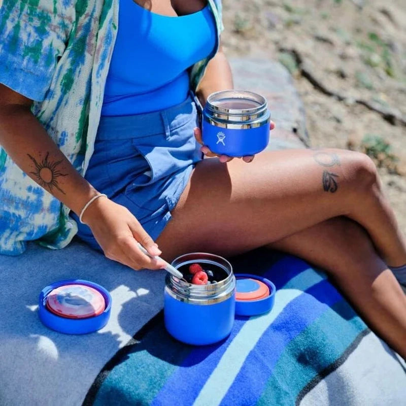 Blå isolerad matburk utomhus, perfekt för picknick och fruktservering