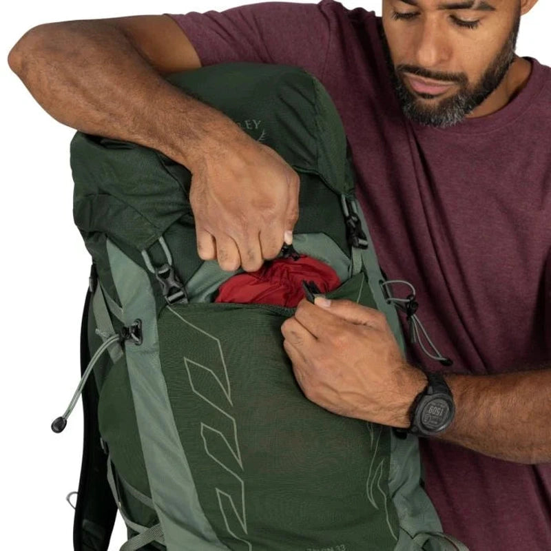 Närbild på man som lägger sak i sidficka på Osprey Talon 33